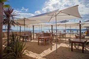 格里莫Holidays by juliano camping 5 etoiles 3149的海滩上一把遮阳伞下的桌椅