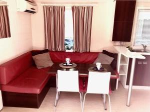 格里莫Holidays by juliano camping 5 etoiles 3149的客厅配有红色的沙发、桌子和椅子