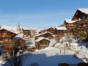 格雷兴apartment EGGERI - das sportliche的一座白雪覆盖的村庄,有木结构建筑和教堂