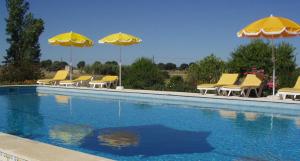 埃武拉Monte Da Serralheira Agro Turismo的一组黄色椅子和遮阳伞,位于游泳池旁
