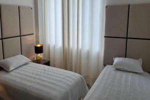 圣克鲁斯Elegante apartamento en Condominio Baruc II的一间卧室设有两张床和一盏靠窗的灯。