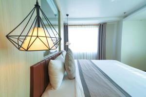 芹苴假日一芹苴酒店的一间卧室配有一张带灯和窗户的床