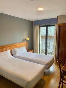 蓬费拉达Hotel Los Templarios的酒店客房设有两张床和窗户。