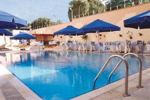 伊斯坦布尔伊斯坦布尔阿克根酒店的一个带蓝伞和桌椅的游泳池