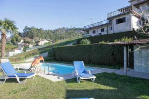 圣托·蒂尔索Casa Rural do Salgueirinho的院子里的游泳池,有两把椅子和一个男人