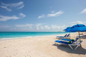 格雷斯湾卡尔港康福特套房度假酒店的海滩上的两把椅子和一把遮阳伞