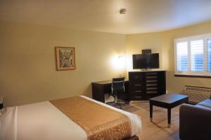 康科德Travelodge by Wyndham Concord的酒店客房配有一张床和一张书桌及一台电视