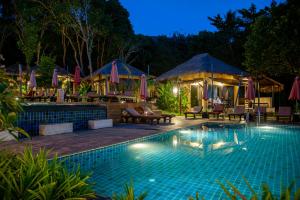 高兰拉兰塔休闲度假酒店的游泳池在晚上提供椅子和遮阳伞