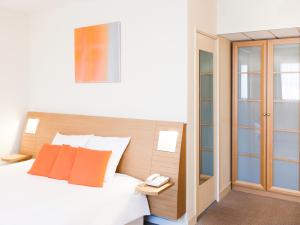 南特诺沃特南特中央伯德卢尔酒店的一间卧室配有带橙色枕头的床和电话