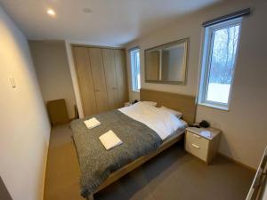 留寿都村Tanuki House - walking distance to Rusutsu Resort的一间卧室配有一张大床和镜子