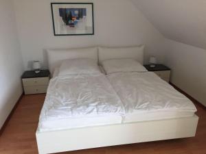 奥斯赛拜-屈隆斯博恩Kuehlungsborn-3-Zi-Ferienwohnung-MOeWENNEST-ARENDSEE的一张白色的床,房间有两个床头柜