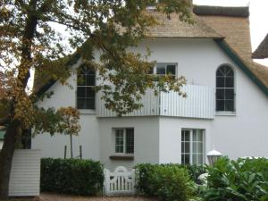 青斯特Zingst-3-Zi-Ferienwohnung-SEELORD-Strandresidenz-Godeke-Michels的白色的房子,有白色的栅栏和树