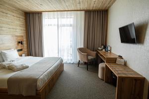 陶里亚蒂Alpen Park的酒店客房配有一张床、一张书桌和一台电视。