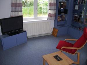 BardowickKleines-Ferienhaus-bei-Lueneburg的客厅配有电视、椅子和桌子