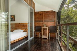 沙璜Beu Ceubeh Cottage Sabang的一间带一张床和两把椅子的卧室,位于阳台