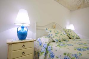 阿尔贝罗贝洛凯旋门索尔农家乐的一间卧室,配有一张睡床,床头灯是蓝色的灯。