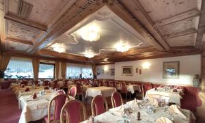 坎皮泰洛迪法萨Hotel Flora Alpina的一间带桌椅和天花板的用餐室
