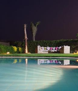 法尤姆Byoum Vacation House的游泳池,晚上配有沙发和棕榈树