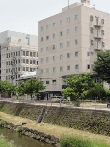 松本松本万屋酒店的一座建筑物,位于河边,建筑背景