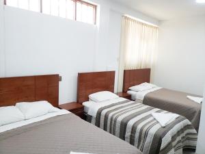 查查波亚斯Shale Hotel的带3张床、条纹毯子和窗户的客房