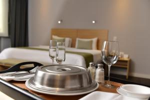 瓜亚基尔统一公园欧罗韦德酒店的酒店客房设有带酒杯的桌子和一张床