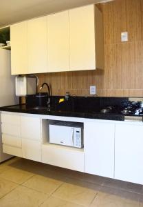 纳塔尔Ana marinho flat 702的厨房配有白色橱柜和微波炉