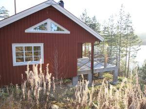 GunsjögårdenChalet in Torsby Municipality Middle with Sauna的红房子,树林里有一个甲板