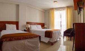 塔克纳Retama Hotel的酒店客房设有两张床和窗户。