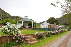 奥茨胡恩De Oude Meul Country Lodge & Restaurant的花园内种有粉红色和白色的花卉,设有凉亭