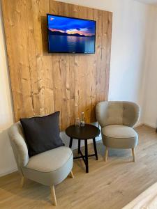 霍兹哈森蓝哥罗迷宾馆的客厅配有两把椅子和墙上的电视