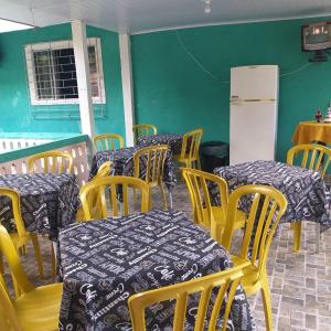 莫雷蒂斯Pousada Recanto Do sagui的餐厅设有桌子、黄色椅子和白色冰箱