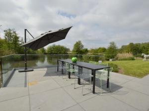EekhoutLovely holiday home Walleken with a pond的庭院配有桌椅和遮阳伞。