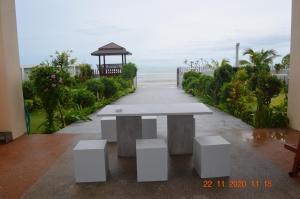 锡春Briya Beachfront Residence的一张白色的桌子和长凳,在海洋前