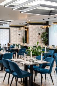 沙罗什保陶克Hotel Bodrog Wellness & Elix Spa的一间配备有桌子和蓝色椅子的用餐室