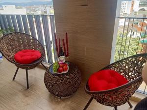 绥和市Royal Khanh Hotel的阳台上配有两把椅子、红色枕头和一碗水果