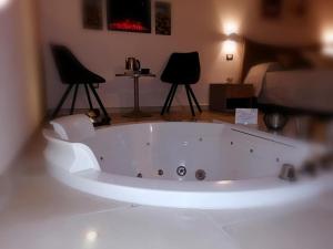 塔兰托Lux Suite的配有两把椅子的房间的白色浴缸