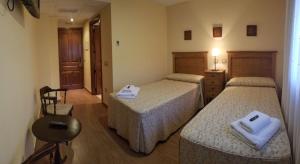 彼德拉拉韦斯posada trastamara的酒店客房设有两张床和一张桌子。