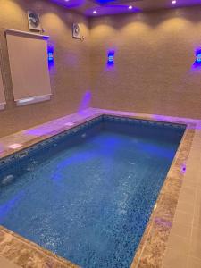 塔伊夫منتجع حديقة الوسام的客房内的大型游泳池配有蓝色的灯光