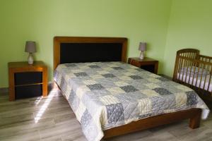 Feteira PequenaCasa dos cinco sentidos的一间卧室配有一张床、两个床头柜和一张婴儿床