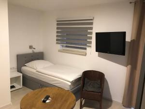 克雷姆林根温伯格酒店的小房间设有床、桌子和电视
