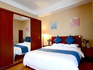 烟台贝壳烟台山公园酒店的酒店客房 - 带两张带蓝色枕头的床