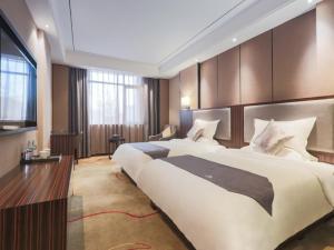 赣州格林东方赣州市章贡区八一四大道汽车站酒店的大型酒店客房设有两张床和电视。