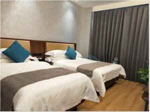 银川格林豪泰银川国际商贸城商务酒店的酒店客房 - 带两张带蓝色枕头的床