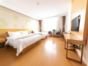 涿州格林豪泰保定市涿州市火车站商务酒店的一间卧室配有两张床、一张桌子和一台电视。