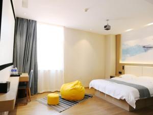 南京VX hotel Nanjing South Railway Station Daming Road Metro Station的一间卧室配有一张床和一个黄色的搁脚凳