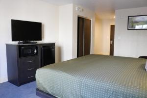 西棕榈滩Pioneer Inn的一间卧室配有一张床和一台平面电视