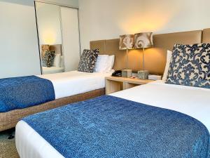 奥克兰Ramada Suites by Wyndham Albany的酒店客房,设有两张床和镜子