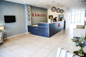 奥克兰Ramada Suites by Wyndham Albany的药店大厅,带柜台和人