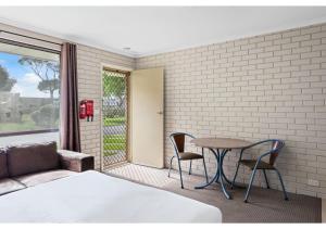 沃纳姆堡Discovery Parks - Warrnambool的卧室配有一张床和一张桌子及椅子