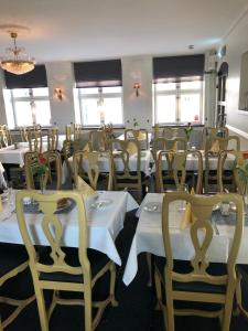 法尔肯贝里Värdshuset Hwitan的一间设有白色桌椅和窗户的用餐室
